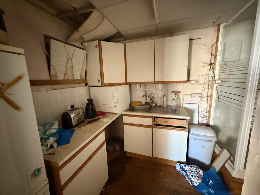 Lot: 100 - COMMERCIAL UNIT FOR REPAIR AND IMPROVEMENT - Small kitchen area with shower enclosure